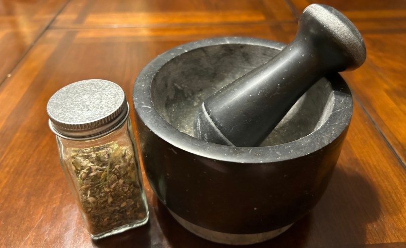 A spice jar of incense and a black stone mortar and pestle.